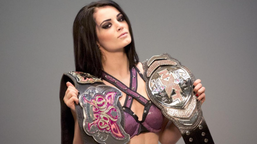 Paige holding two belts